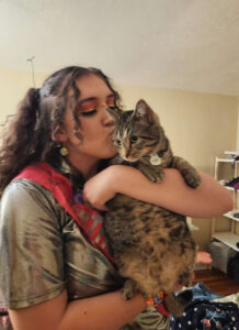 Rylee holding and gently kissing her tabby cat Miles, showing their close bond.